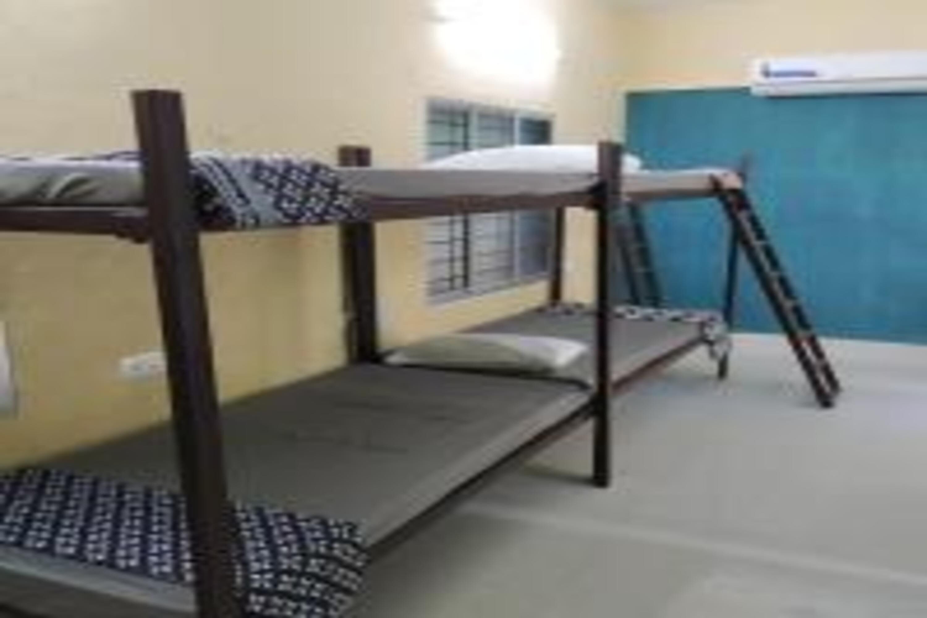 Une chambre avec un lit superposé, une fenêtre et un appareil de climatisation fixé au mur.