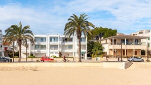 Un edificio costero con balcones, palmeras y un primer plano de arena.