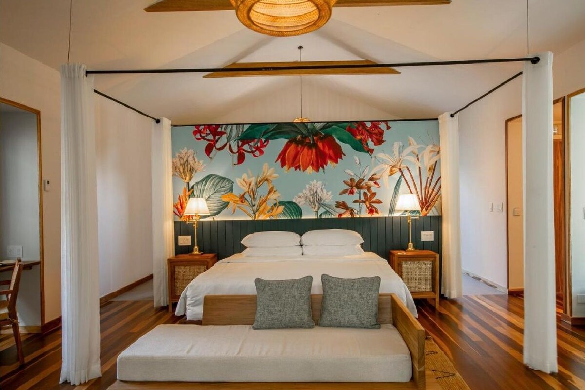 A bedroom with a bed, nightstands, a ceiling fan, and a floral mural on the wall.