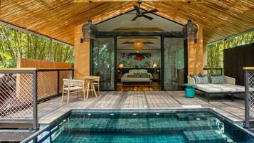 A poolside area with a wooden deck, a glass-enclosed bedroom, and a seating area with a sofa and chairs.