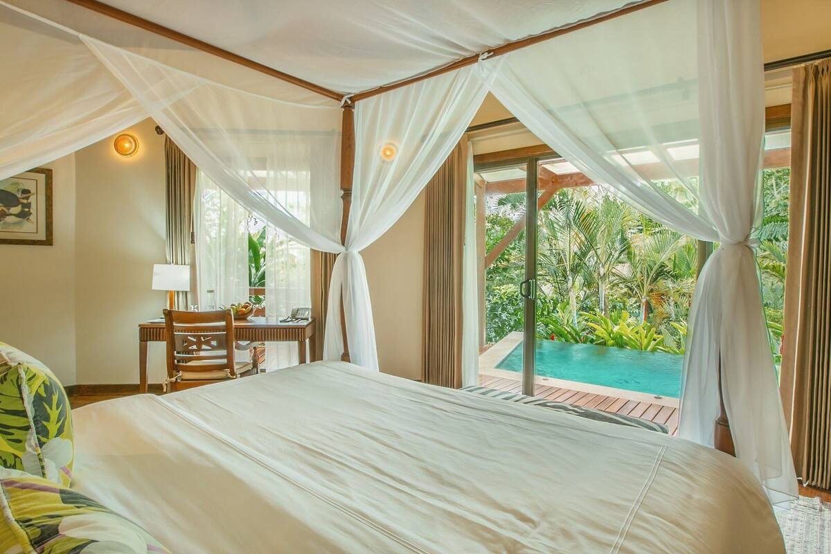 Ein Schlafzimmer mit Bett, Schreibtisch, Stuhl und Blick auf einen Pool.