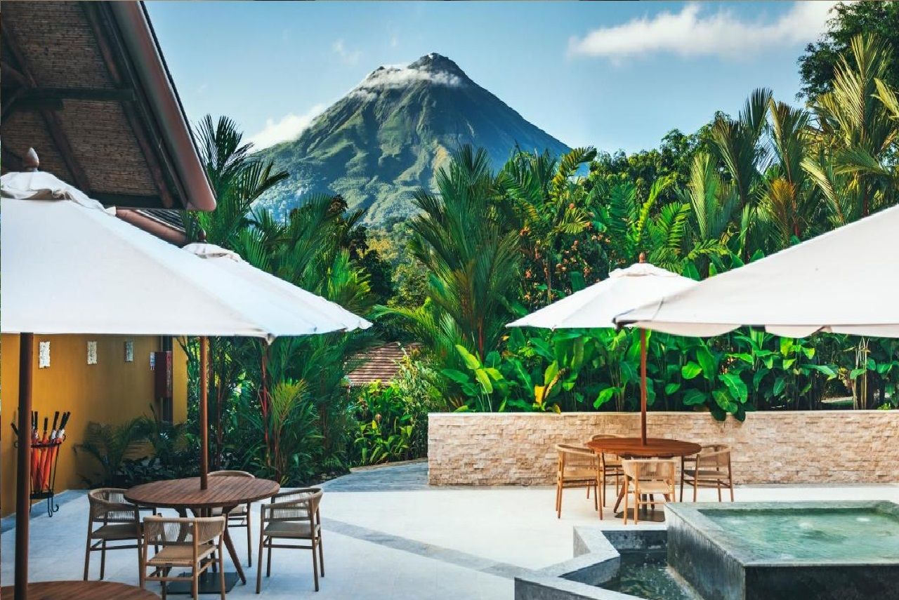 A patio with outdoor seating, a stone wall, and a view of a mountain.