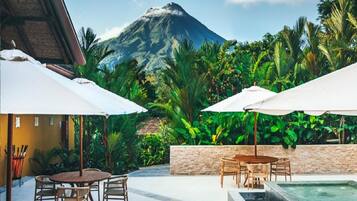 A patio with outdoor seating, a stone wall, and a view of a mountain.