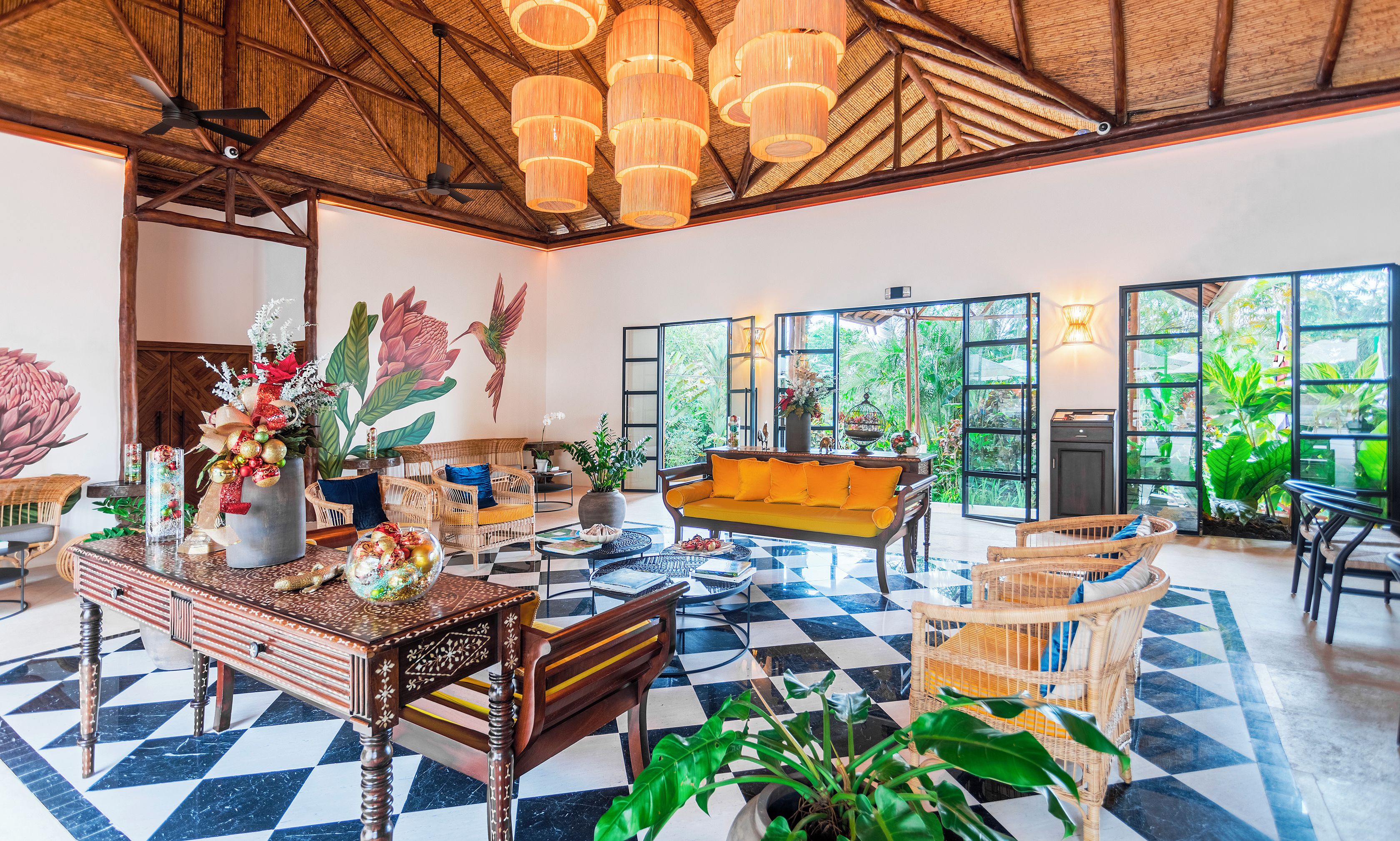 A spacious room with a checkered floor, wicker furniture, and a large window offering a view of greenery.