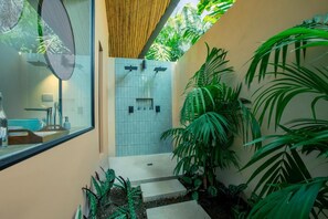 A modern bathroom with a glass shower enclosure, tiled walls, and lush green plants.