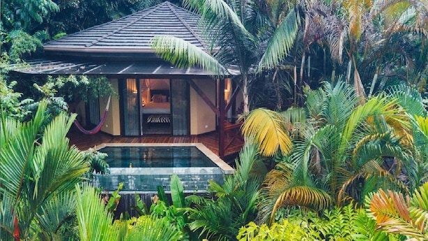 A secluded villa with a glass-enclosed room, a pool, and lush tropical vegetation. - Nayara Gardens (La Fortuna)