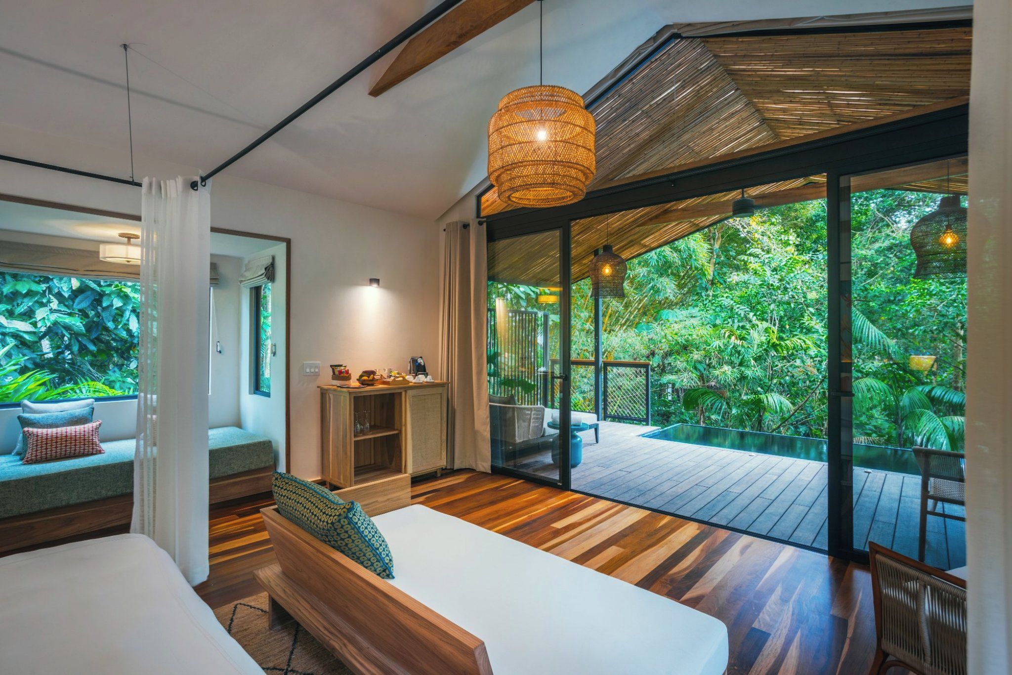 Un dormitorio moderno con un amplio ventanal, piso de madera y vistas a un follaje exuberante.