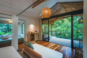 Un dormitorio moderno con un amplio ventanal, piso de madera y vistas a un follaje exuberante.