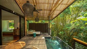 A modern outdoor deck with a glass-bottomed pool, wooden furniture, and a bamboo ceiling.