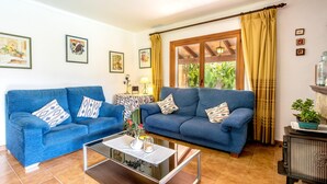 A living room with two blue sofas, a glass coffee table, and a wooden cabinet. - SOL ROMA. 3 bedrooms villa near Pollensa (Pollensa)