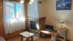 Un salon confortable avec une cheminée, un téléviseur et une table.