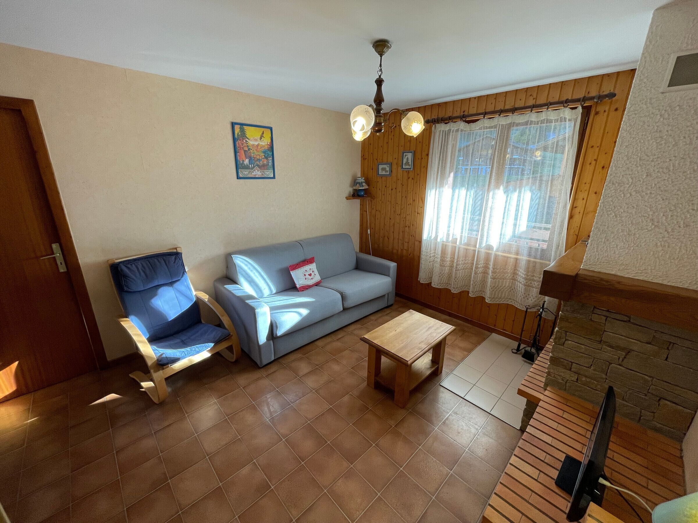 A living room with a sofa, a chair, a small table, and a television.