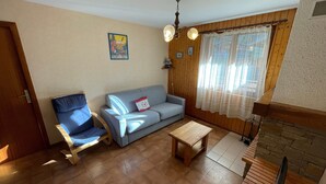 Un salon avec un canapé, un fauteuil, une petite table et un téléviseur.