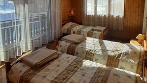 Une pièce confortable avec deux lits, un plancher en bois et une fenêtre avec des rideaux.