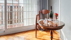 A room with a wooden floor, a glass table with a bottle and strawberries, and a chair. - matarolux2 · 25km from Barcelona , Beach 200 meters (Mataro)