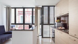 A modern kitchen with a central island, a dining area with a sofa, and large windows with blinds. - 25 km Barcelona , 100 meters from the beach (mat6) (Mataro)