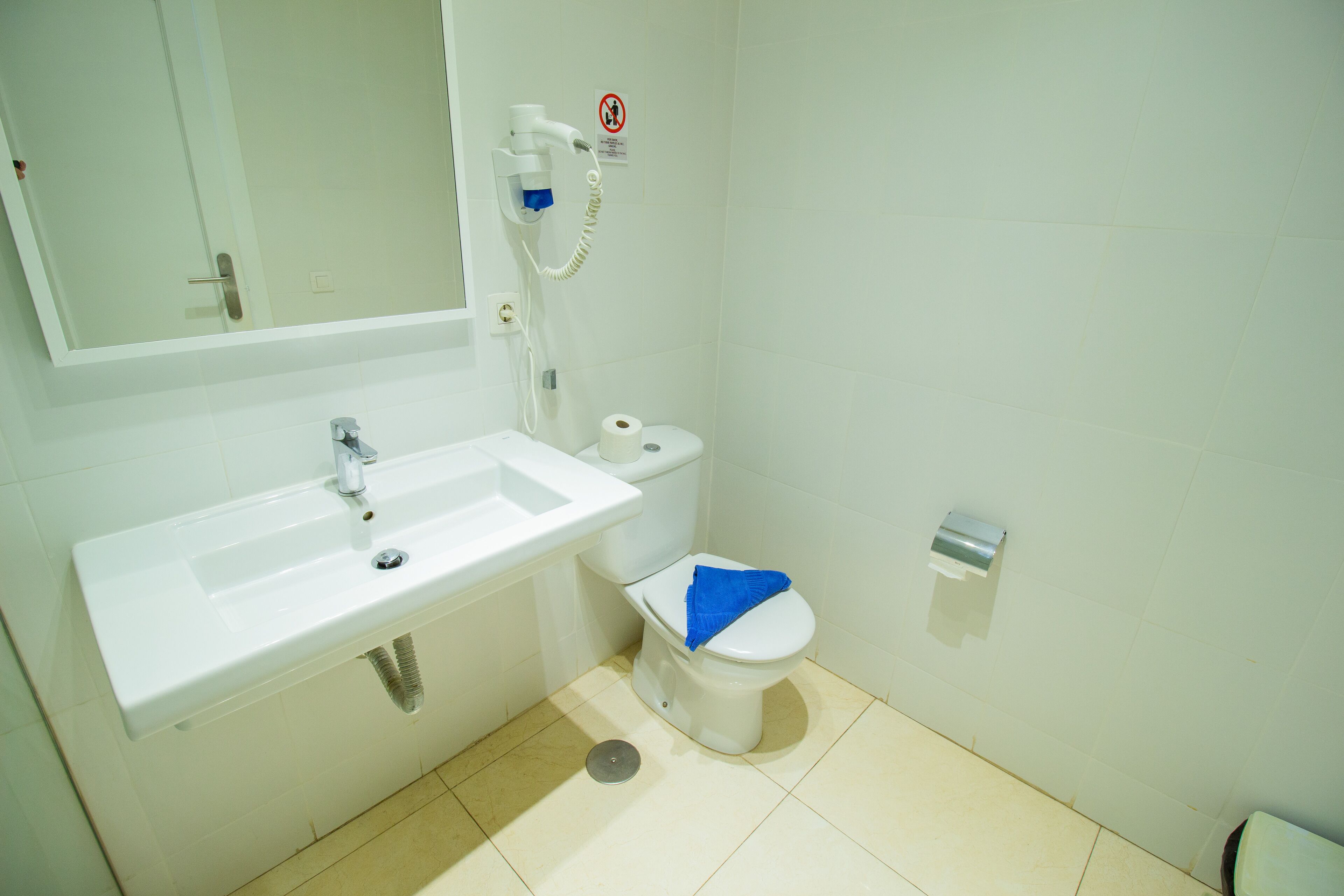 Un baño con un lavamanos blanco, inodoro y un secador de manos montado en la pared.