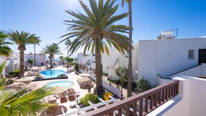 A rooftop pool area with palm trees, lounge chairs, and a clear blue sky. - Apartamentos Flamingo (Tías)