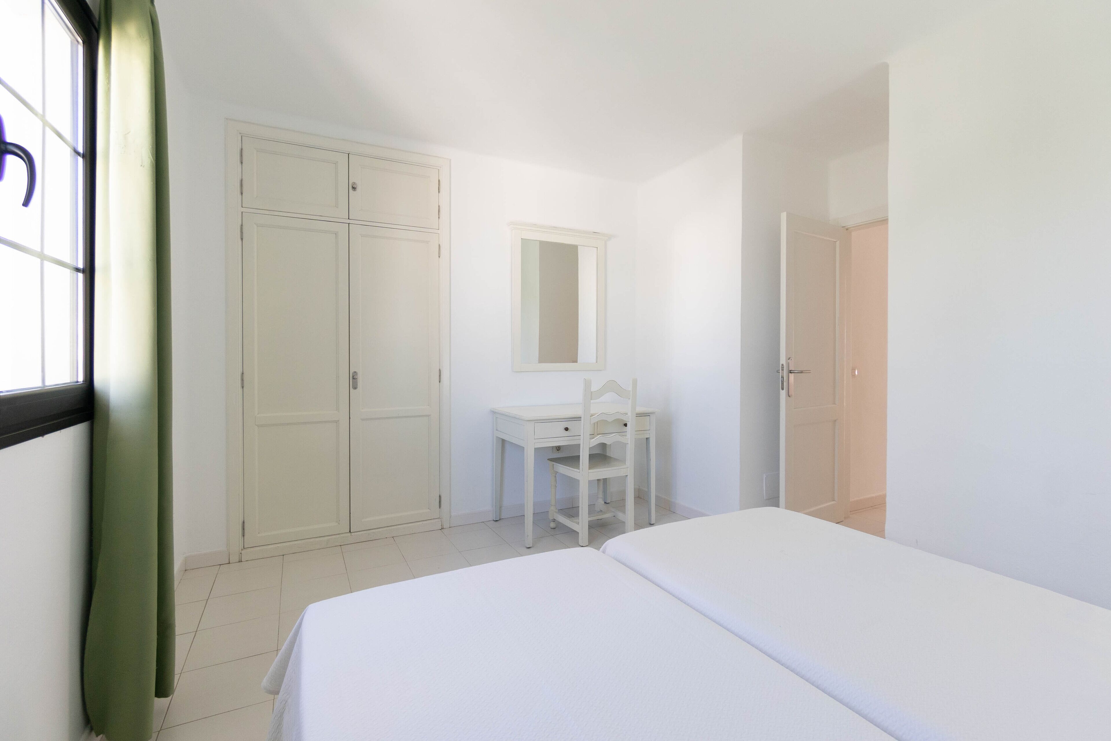 Quarto com cama, escrivaninha, cadeira, guarda-roupa e espelho.