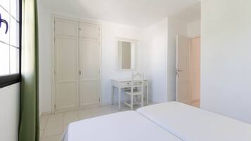 Quarto com cama, escrivaninha, cadeira, guarda-roupa e espelho.