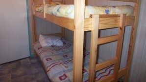Ein Stockbett mit Holzgestell und einem gemusterten Bettbezug.