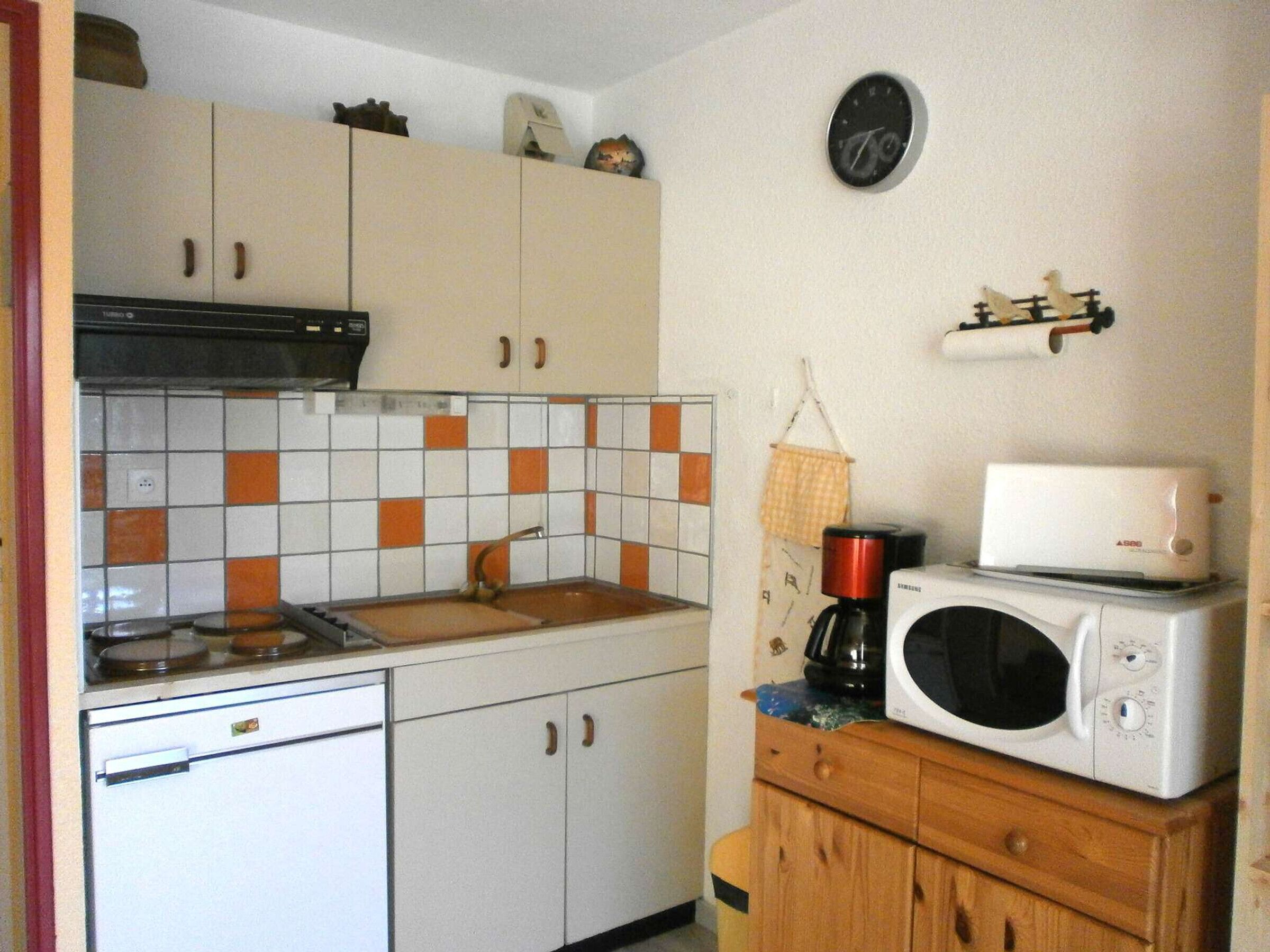 Et køkken med mikrobølgeovn, brødrister og vask.