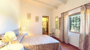 A bedroom with a bed, bedside tables, a window with curtains, and a door leading to a bathroom. - CAN MORANTA ( VERD ). Beautiful villa near Pollensa (Alcúdia)