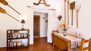 A room with a wooden bookshelf, a dining table with a white tablecloth, and rustic wall decorations including wooden tools. - CAN MORANTA ( VERD ). Beautiful villa near Pollensa (Alcúdia)