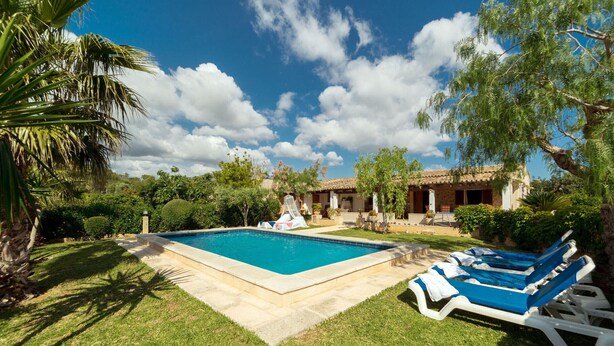 A swimming pool with lounge chairs, a well-maintained lawn, and a building with a tiled roof. - CAN MORANTA ( VERD ). Beautiful villa near Pollensa (Alcúdia)
