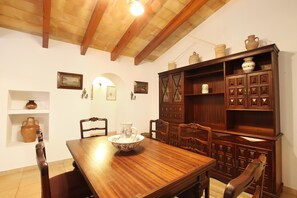 Un coin repas comprenant une table en bois, des chaises, un grand saladier et un meuble contenant des objets décoratifs.