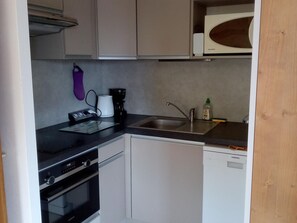 Une cuisine compacte équipée d’un lave-vaisselle, d’un four et d’un four à micro-ondes.