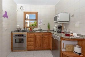 A kitchen with wooden cabinets, a built-in oven, a microwave, and a sink.