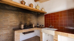 Eine Küche mit Backsteinwand, einem Holzboden mit Keramik und einem Backsteinofen sowie einer roten Fliesenrückwand.