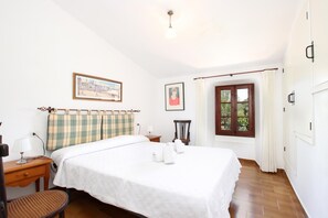 A neatly arranged hotel room with a bed, a chair, a desk, and a window with curtains. - PUNXA. Lovely stone-clad villa with large gardens surrounded by fruits and mountains (Pollensa)
