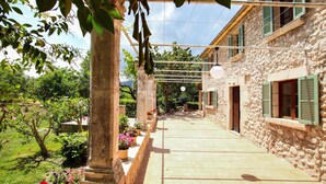 Un bâtiment en pierre doté d’un espace extérieur abrité, de plantes en pot et surplombé d’un ciel dégagé.