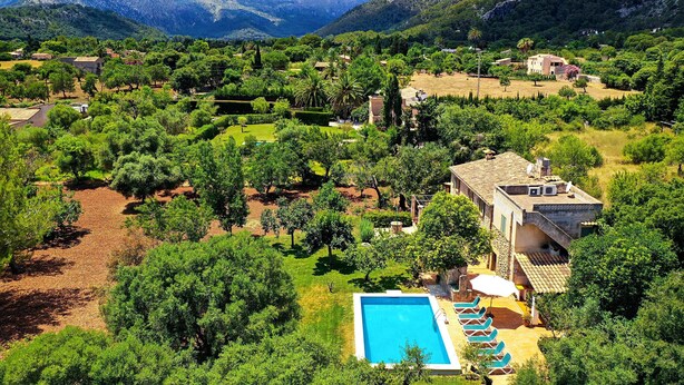 Une villa avec piscine, entourée d’une végétation luxuriante et de montagnes.