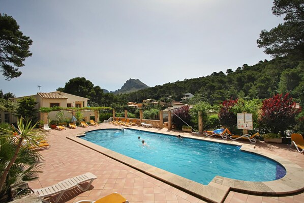 A swimming pool with lounge chairs and a mountain in the background.