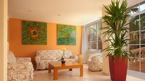 Een woonkamer met bloemensofa's, een houten salontafel en een grote potplant.