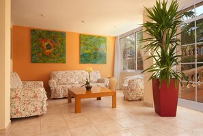 A living room with floral sofas, a wooden coffee table, and two abstract paintings on the wall.