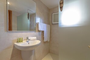 A bathroom with a white sink, mirror, and a wooden door.