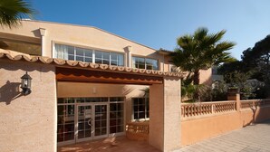 A two-story building with a tiled entrance and a balcony. - PINOS ALTOS 15. Lovely apartment in Cala San Vicenç (Cala San Vicente)