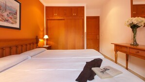 Une chambre d’hôtel avec un grand lit, une armoire en bois, une table de chevet avec une lampe et un tableau au mur.