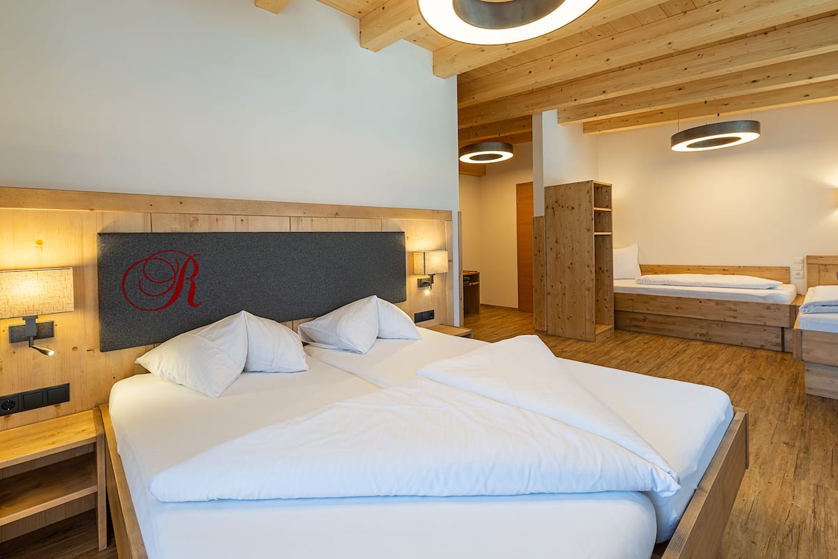 Una habitación de hotel moderna con una cama grande, cabecera de madera y una lámpara circular sobre la cama.