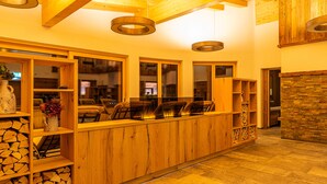 A wooden bar area with shelves, a fireplace, and a stone wall. - Hotel Garni Romantik (Fuegenberg)
