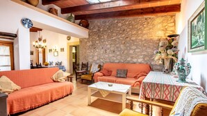 A cozy living room with a stone wall, a sofa, a coffee table, and a patterned tablecloth. - ROSA. Traditional villa near Pollensa town (Pollensa)