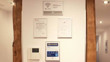 Una pared con varios documentos enmarcados y un cartel de Wi-Fi.