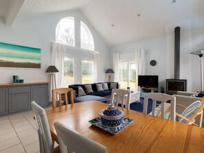 A spacious living room with a wooden dining table, a sofa, a TV, and a fireplace.
