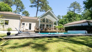 Une maison à deux étages avec une piscine, une terrasse et un jardin.