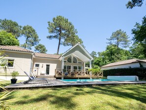 A two-story house with a swimming pool, a deck, and a garden.