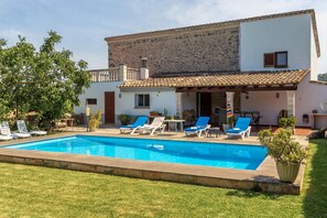 Uma casa de dois andares com piscina, área de estar externa e fachada de pedra.